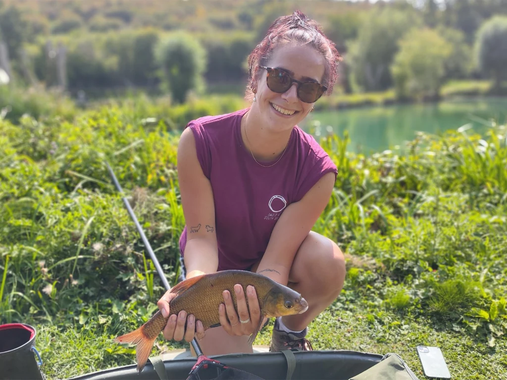 Women holding fish next to the waters edge