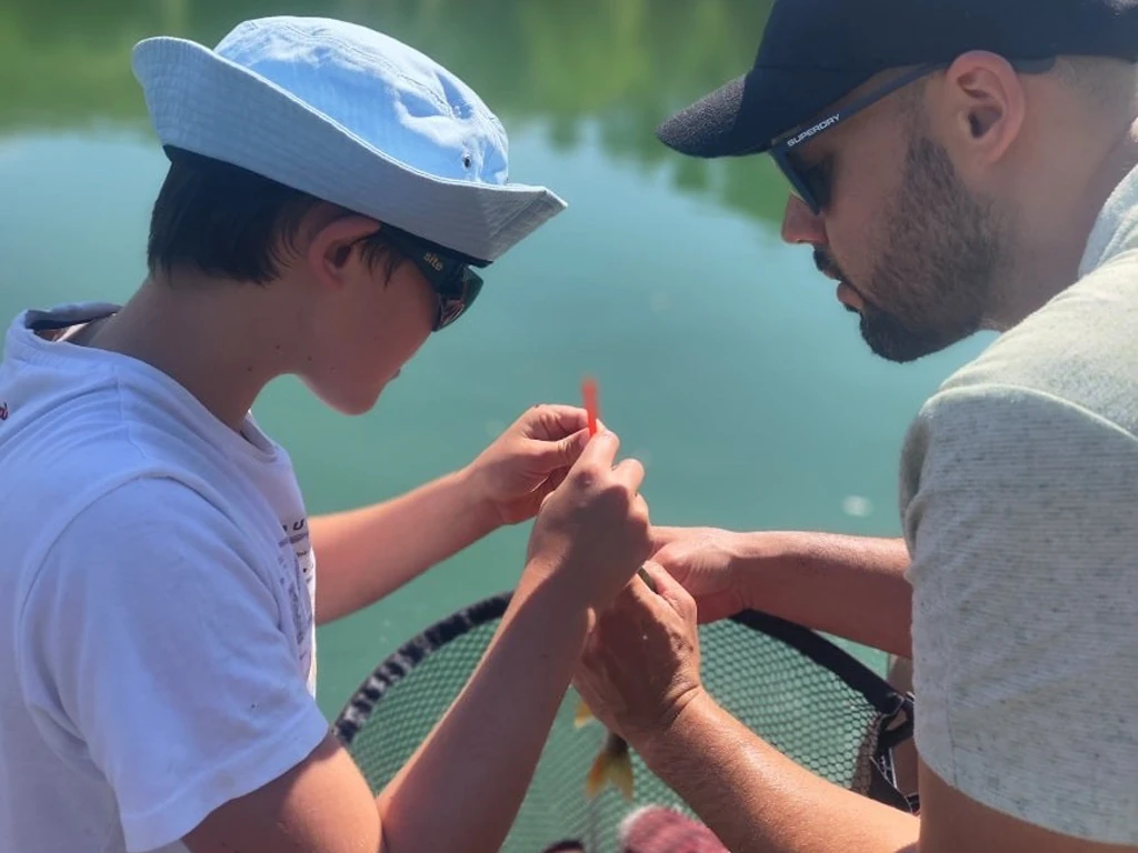 Father and son working together to unhook fish.
